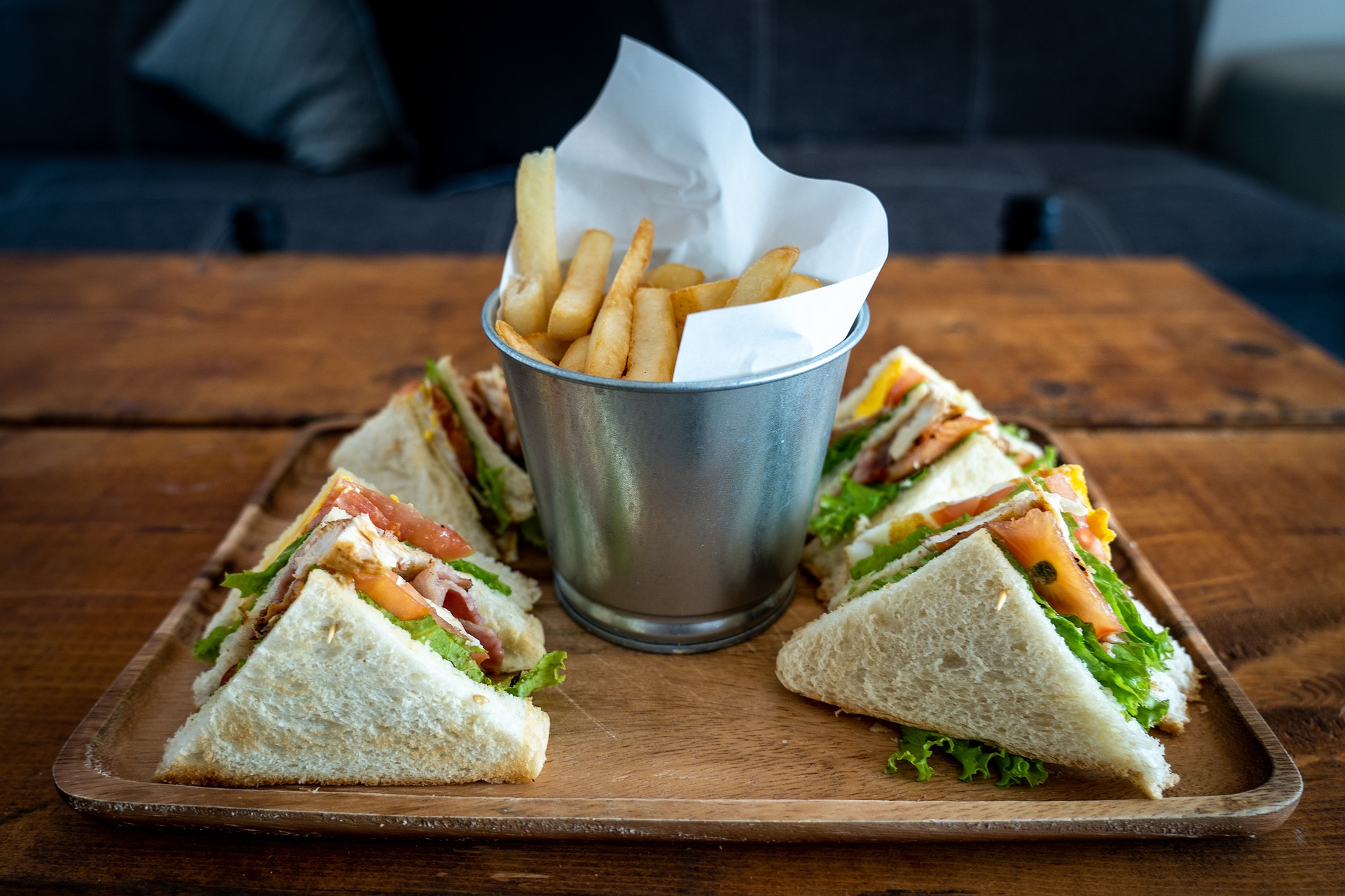 sandwiches on wooden tray with bucket of chips in the middle sandwiches on wooden tray with bucket of chips in the middle