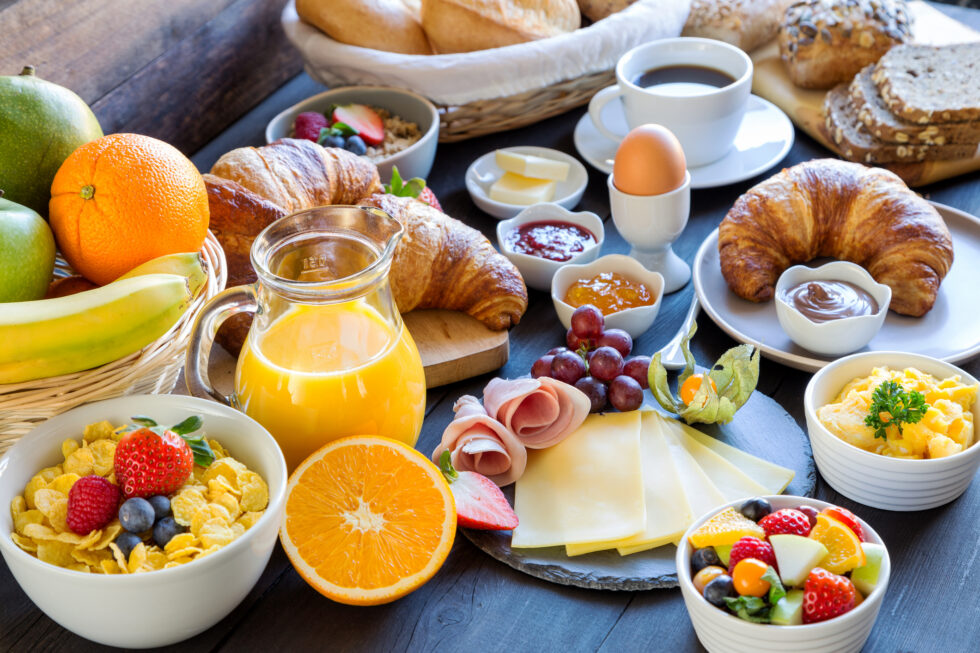 Brunch Meal Catering Table set for brunch with a variety of meals including eggs on toast, pancakes, fresh fruit, pastries, and coffee, arranged in a bright, inviting setting.