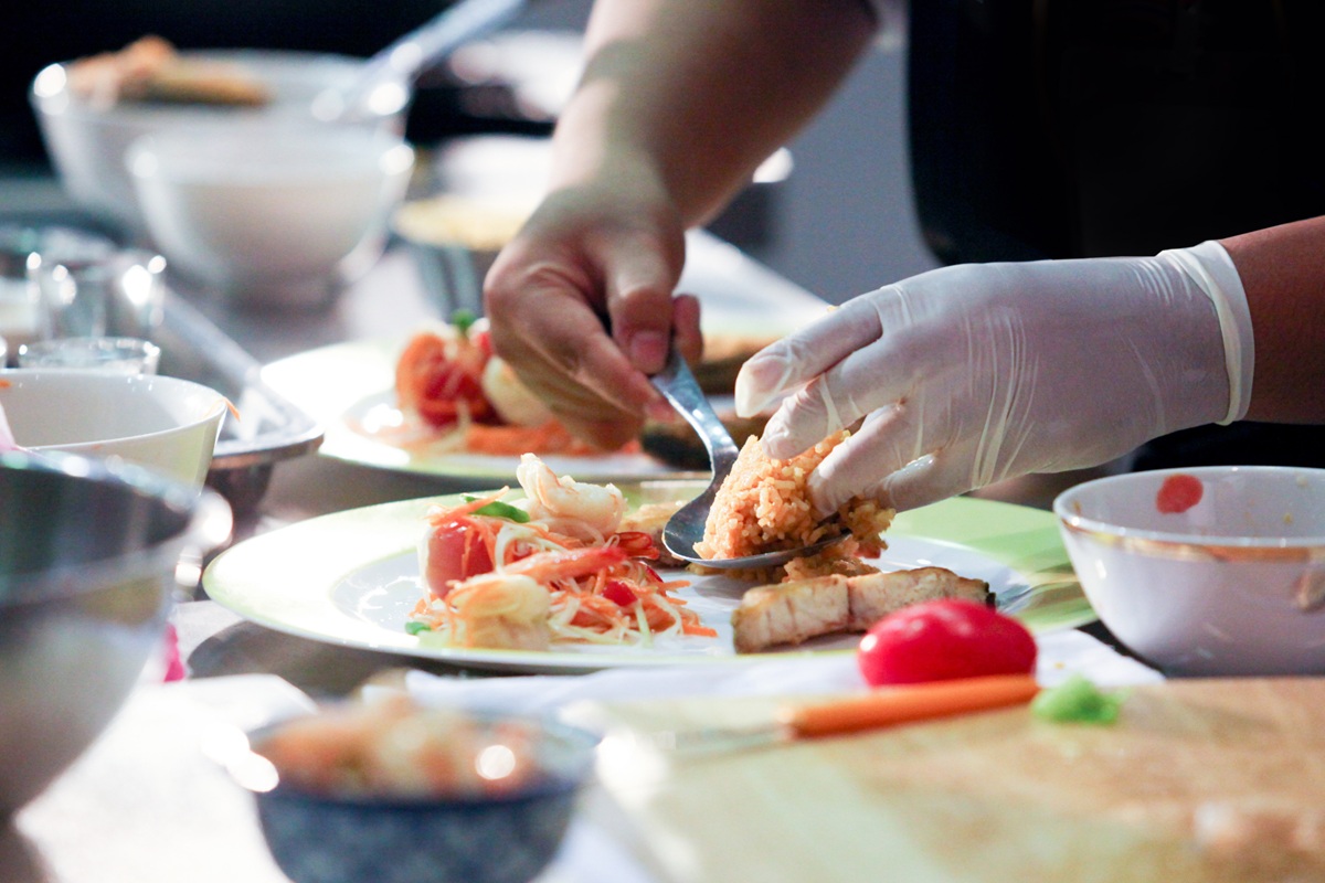 event catering Chef carefully arranging gourmet dishes on plates in a professional kitchen.