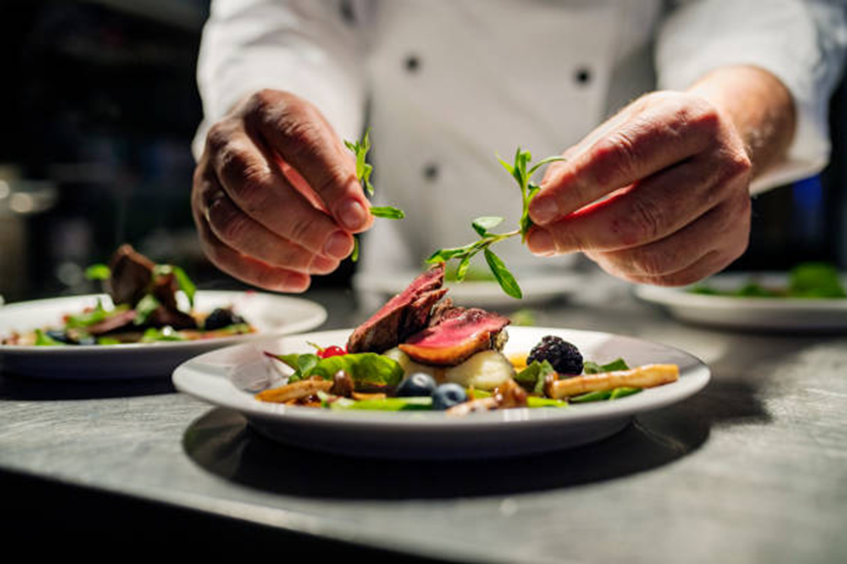 seated dinner Standing Fork chef plating meals fresh on-site during a catered event.